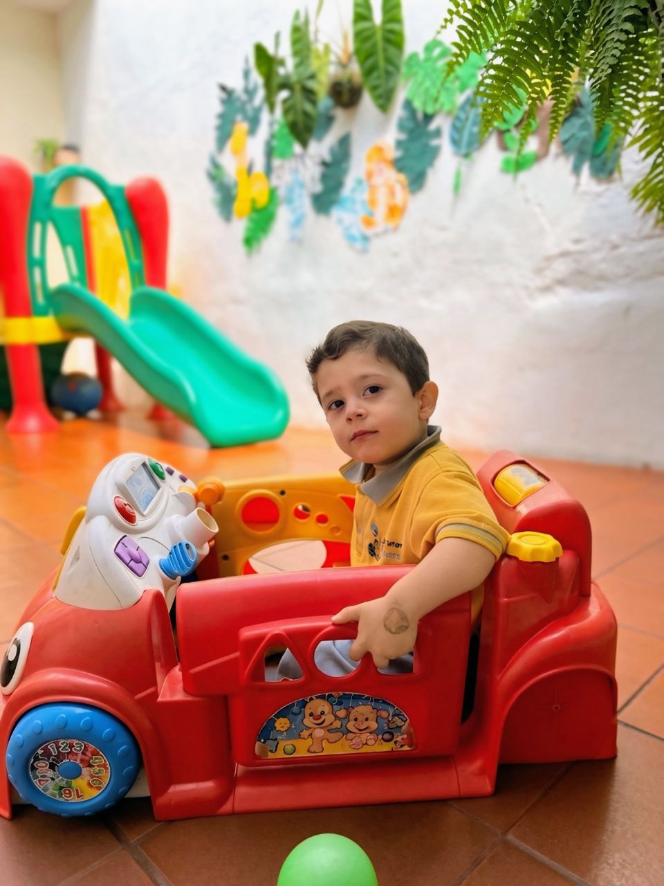 Niño feliz en coche de juguete en el jardín de Caracolitos