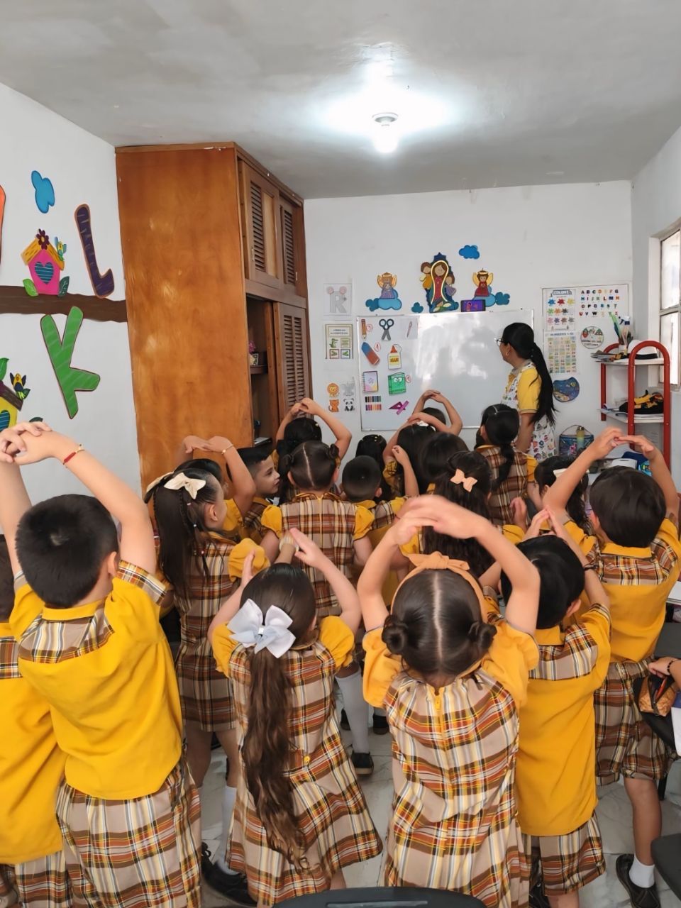 Niños en clase participando activamente con su profesora